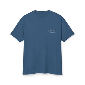 May include: A blue crew neck t-shirt with the phrase "joie de vivre" printed in a light blue script on the upper left chest. The shirt is made of a soft material and has short sleeves.