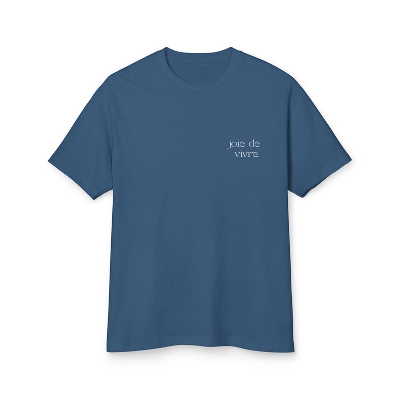 May include: A blue crew neck t-shirt with the phrase "joie de vivre" printed in a light blue script on the upper left chest. The shirt is made of a soft material and has short sleeves.