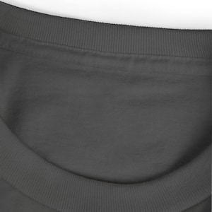 May include: Close-up of a dark gray crew neck sweatshirt. The neckline and collar are ribbed. The fabric appears soft and smooth. The image is well-lit, highlighting the texture and color of the garment.