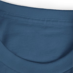 May include: Close-up of a blue crew neck sweatshirt. The neckline and the top of the shoulders are visible. The neckline has a ribbed texture, and the fabric is a solid, medium blue color.