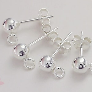 May include: Four silver earring posts with round balls at the end. Each post has a loop at the end for attaching a charm or dangle.