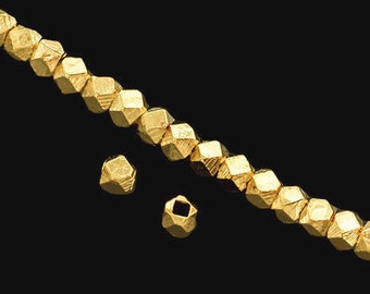 May include: A strand of gold-colored beads strung on white thread. The beads are faceted and have a geometric shape. Two additional beads are shown separately.
