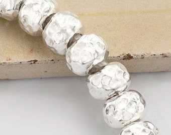 Può includere: Una collana di perle d'argento con un cordoncino bianco. Le perle sono rotonde e hanno una texture martellata.