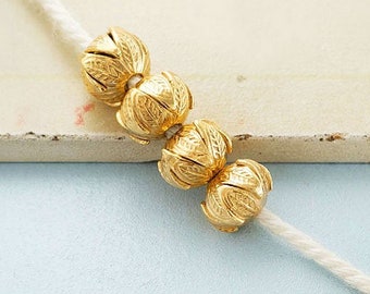 May include: Four gold-colored beads with a textured surface are strung on a white cord.