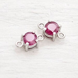 以下が含まれることがあります： 中央に赤い宝石がついた、銀色のコネクターチャームが2つ。各チャームには、ジュエリーに取り付けるためのループが2つあります。