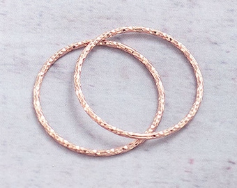 May include: Two delicate rose gold hoop earrings with a textured finish.