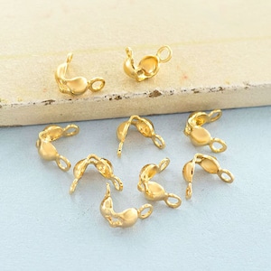 May include: A set of ten gold-toned metal clasps for jewellery making. The clasps are shaped like a small loop with a curved bar that snaps into place.
