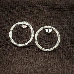 May include: A pair of silver hammered circle earrings. The earrings are simple and elegant, and would make a great gift for any occasion.