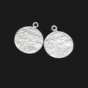 May include: Two silver round pendant charms with a textured surface. The charms have a loop at the top for attaching to jewellery.