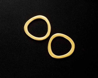 May include: Two gold-colored, irregular-shaped earrings against a black background. The earrings have a smooth, polished finish and a minimalist design. The earrings are a warm, yellow-gold color.