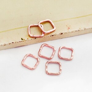 May include: Six rose gold square jump rings. The jump rings are about 1 cm in diameter.