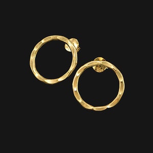 May include: A pair of gold-toned hoop earrings with a textured, wavy design.