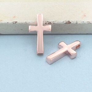 May include: Two rose gold cross charms. The charms are simple and elegant, with a smooth finish.