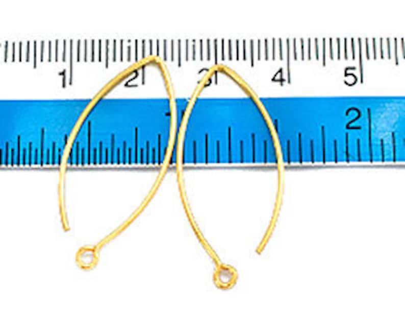 May include: Two gold-colored earring hooks, each measuring approximately 2 inches in length, are displayed against a blue ruler.