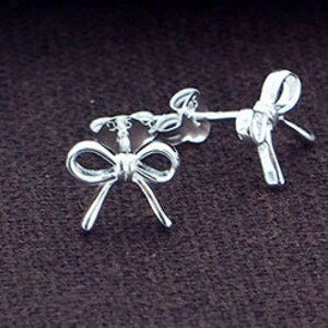 May include: A pair of silver bow-shaped stud earrings.