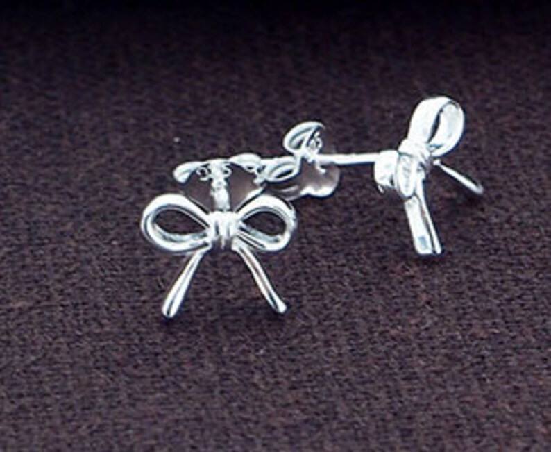 May include: A pair of silver bow-shaped stud earrings.