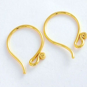 May include: A pair of gold-toned earring hooks with a simple, elegant design. Each hook features a small, coiled loop at the end.