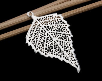 Op de afbeelding: Een zilverkleurige bladhanger met ingewikkelde open details, die lijken op de nerven van een echt blad. De hanger heeft een kleine lus aan de bovenkant om op te hangen. Het blad ligt op twee houten stokjes tegen een zwarte achtergrond.