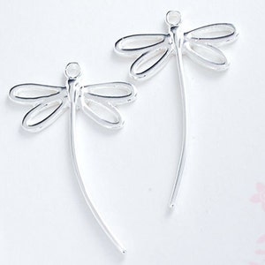 Peut inclure: Deux breloques argentées en forme de libellule. Chaque breloque présente un design ajouré délicat avec des ailes et un corps fin et incurvé. Idéal pour la fabrication de bijoux ou les projets d'artisanat.