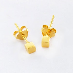 May include: A pair of gold-toned cube stud earrings. The earrings have a simple, minimalist design.