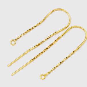 Puede incluir: Un par de cierres de pendientes dorados con un diseño de cadena. Los cierres son de metal y tienen un bucle en la parte superior para sujetar los pendientes.