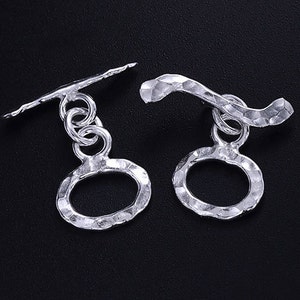 Pu&ograve; includere: Due chiusure a scatto in argento con anelli ovali testurizzati. Le chiusure sono progettate per l'uso con collane, braccialetti o altri gioielli.