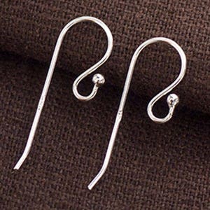 Könnte beinhalten: Ein Paar silberne Ohrhaken mit einer kleinen Kugel am Ende jedes Hakens.