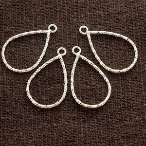 May include: Four silver teardrop-shaped earring findings with a textured surface.
