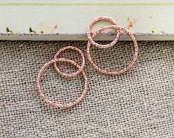 May include: A pair of rose gold earrings with a textured finish. Each earring features three interlocking circles.