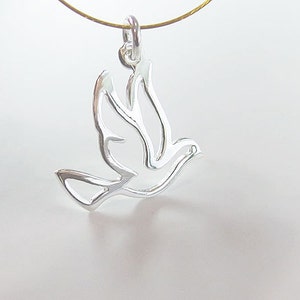 May include: A silver-colored pendant in the shape of a dove, suspended from a thin gold-colored chain. The dove design is open, with the wings and body outlined in metal. The pendant is likely made of sterling silver.