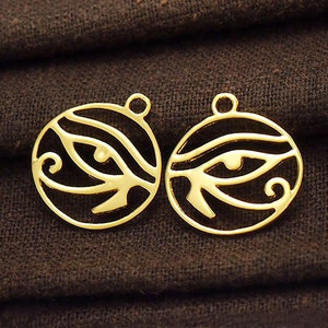 Puede incluir: Dos dijes de metal de color dorado en forma de c&iacute;rculo con un dise&ntilde;o de ojo de Horus. Los dijes tienen un agujero en la parte superior para sujetarlos a un collar o pulsera.