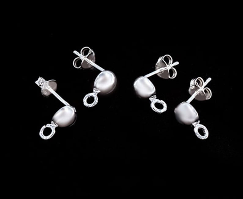 May include: Four silver earring findings with a loop at the bottom. The findings have a small ball at the top and a post with a butterfly back.