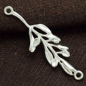May include: Silver-toned metal charm featuring a detailed design of a branch with leaves and berries. The charm has two loops at the top and bottom for attaching to jewelry.