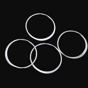 May include: Four silver-colored metal rings, arranged in a circular pattern, on a black background.