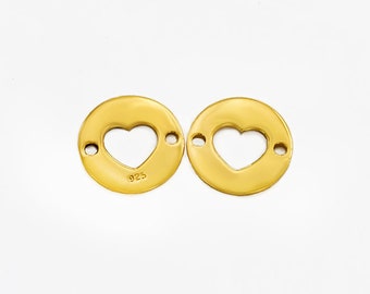 May include: Two gold-toned metal charms with a heart-shaped cutout. The charms have two small holes on each side for attaching to jewelry. One charm is stamped with "925".