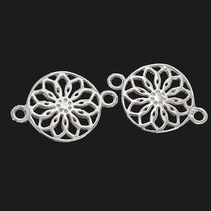 May include: Two silver-toned metal connector charms with a circular, intricate, mandala-like design. Each charm has two loops for attaching to jewellery.