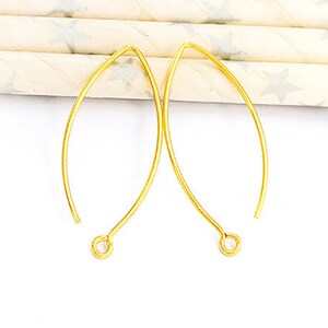 May include: Two gold-toned earring wires with a loop at the end. The wires are curved into a teardrop shape.