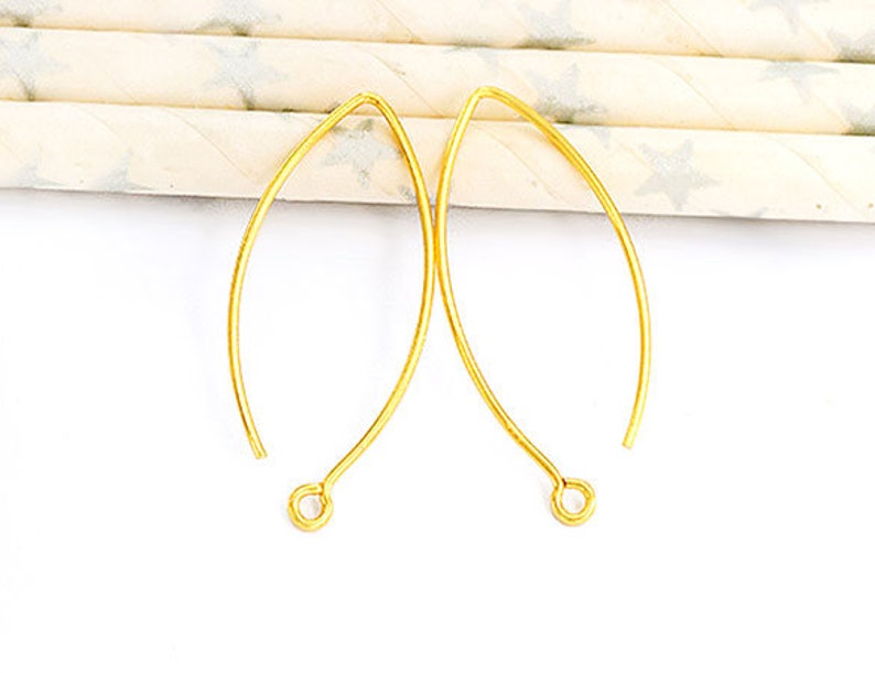 May include: Two gold-toned earring wires with a loop at the end. The wires are curved into a teardrop shape.