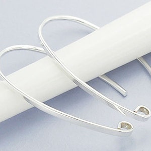 May include: A pair of silver-toned earring hooks with a curved shape and a small heart-shaped loop at the end.