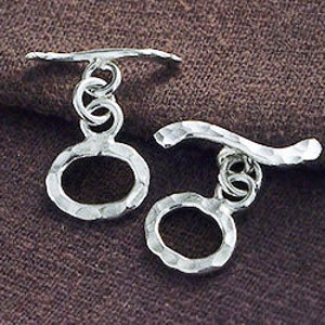 Pu&ograve; includere: Un paio di orecchini pendenti in argento con ciondoli circolari martellati e barre in argento curve.