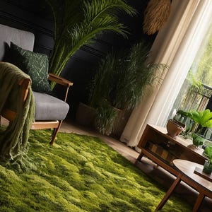 May include: A living room scene featuring a vibrant green moss-like rug. A gray armchair with a green patterned pillow and blanket sits near a window with sheer curtains. Decorative plants and wooden furniture complete the interior.
