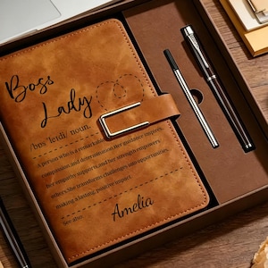 Può includere: Un diario in similpelle marrone in una scatola con il testo Boss Lady, una definizione in stile dizionario e il nome Amelia. Il set include una penna abbinata e una cartuccia di ricambio, presentati in una scatola regalo marrone.
