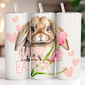 Könnte beinhalten: Weißer Becher mit einer Aquarellillustration eines braunen Hasen, rosa Tulpen und dem Text "HAPPY EASTER" in Rosa. Rosa Herzen sind über das Design verstreut. Der Becher hat einen transparenten Strohhalm.