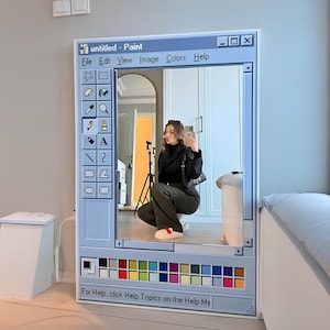 May include: A large, rectangular mirror designed to resemble a classic Windows Paint window. The mirror features a light blue frame with a toolbar, color palette, and the text "untitled - Paint". The reflection shows a person taking a photo.