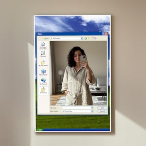 Könnte beinhalten: Gerahmtes Kunstwerk, das eine Windows XP-Oberfläche nachahmt. Es zeigt eine Frau, die ein Selfie in einem "Eigene Bilder"-Fenster macht, vor einem Hintergrund aus Himmel und Gras, für einen nostalgischen Effekt.