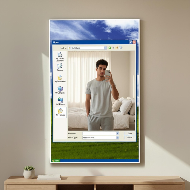 May include: A framed art print featuring a man taking a selfie, overlaid with a Windows XP interface. The background shows a bedroom scene. The print has a green grass and blue sky background.