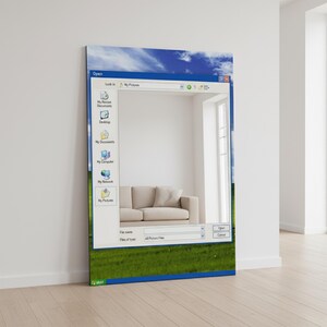 May include: A rectangular mirror with a printed design resembling a Windows XP interface. The mirror's frame is a blue border with a green grass and blue sky background. The reflection shows a beige sofa in a white room.