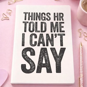 May include: A white notebook with the text "THINGS HR TOLD ME I CAN'T SAY" in bold black letters. The notebook is surrounded by gold paperclips, a pink pen, and a cup of coffee on a pink surface.