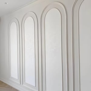 K&ouml;nnte beinhalten: Eine Wand mit wei&szlig;er Wandverkleidung und drei markanten Bogensegmenten. Die Zierleisten bilden einen erhabenen, abgerundeten Rahmen um jeden Abschnitt, der sich von einer glatten, matten wei&szlig;en Oberfl&auml;che von der Decke bis zum Boden abhebt.