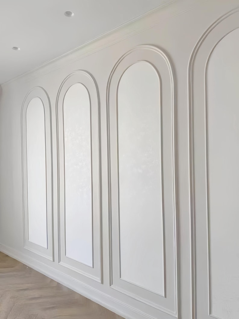 K&ouml;nnte beinhalten: Eine Wand mit wei&szlig;er Wandverkleidung und drei markanten Bogensegmenten. Die Zierleisten bilden einen erhabenen, abgerundeten Rahmen um jeden Abschnitt, der sich von einer glatten, matten wei&szlig;en Oberfl&auml;che von der Decke bis zum Boden abhebt.